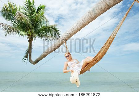 view of nice young lady swinging  in hummock on tropical beach