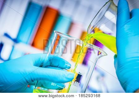 Scientist mixes two colourful substances in a laboratory. Pouring liqiud to a flask. Chemistry and science equipment.