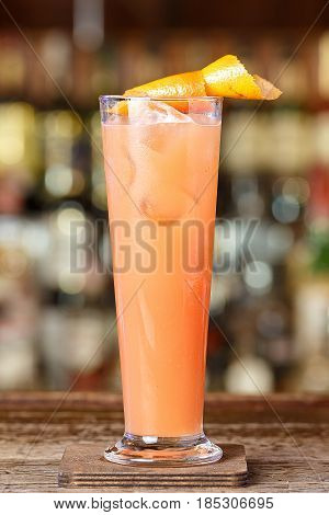 Refreshing cocktail with grapefruit is on the bar in a nightclub on a blurry background of bottles with alcohol