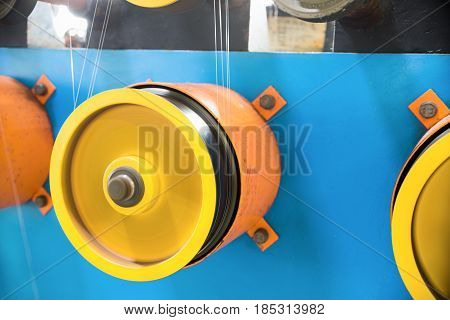 A rotating wheel rewinds a thin silver wire. Automatic winding machine.