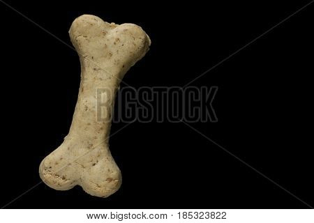 Dog biscuit on black background to connote a concept of feeding animals