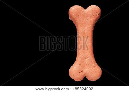 Dog biscuit on black background to connote a concept of feeding animals