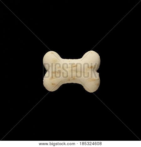 Dog biscuit on black background to connote a concept of feeding animals