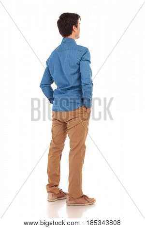 back view of a relaxed casual man with hands in pockets, full body picture of white background