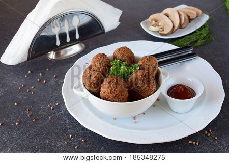 Balls with buckwheat and mushrooms in a white bowl on a grey abstract background. Dieting. Fasting food. healthy eating concept