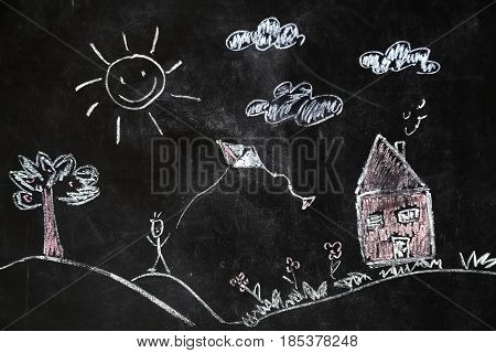 children's chalk drawing of house and sun on black background the concept of nature and the environment