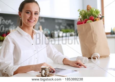 Young woman planning expenses and paying bills on her kitchen