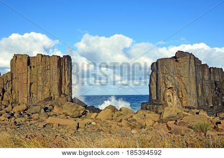Waves breaking in the gap between basalt rock formations with a view to the sea at Bombo Headland quarry, New South Wales coast, Australia