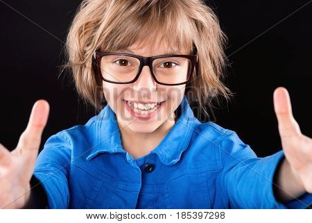 Emotional portrait of attractive caucasian little student girl wearing eyeglasses. Funny cute smiling child 10 year old looking at camera on black background.
