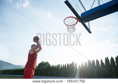 Young man jumping and making a fantastic slam dunk playing streetball, basketball. Urban authentic.