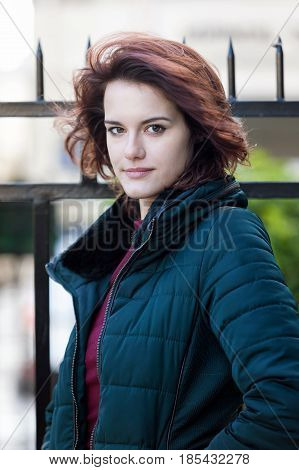 Young beautiful girl's portrait with dark hair with fence on the background
