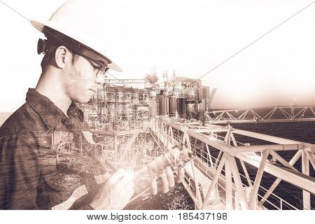 Double exposure of Engineer or Technician man with safety helmet operated platform or plant by using tablet with offshore oil and gas platform background for oil and gas business concept.