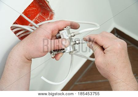 Man's hands inserts a TV antenna cable to a splitter.