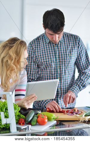 Couple in home kitchen using electronic tablet.