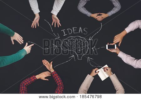 Teamwork concept - top view of six people generate ideas. Blackboard table.