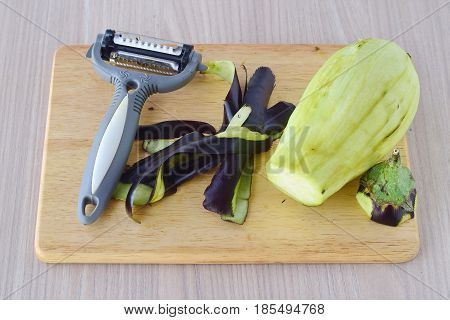 Step by step cooking. Peeled aubergine on a wooden cutting board on a wooden background