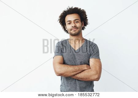 Portrait of stong and handsome african man looking at camera posing with crossed arms over white background. Confident entrepreneur or student. Copy space.