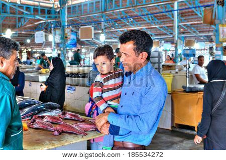 Bandar Abbas Hormozgan Province Iran - 16 april 2017: The fish market the tuna seller is talking to the buyer who is holding the little boy in his arms.