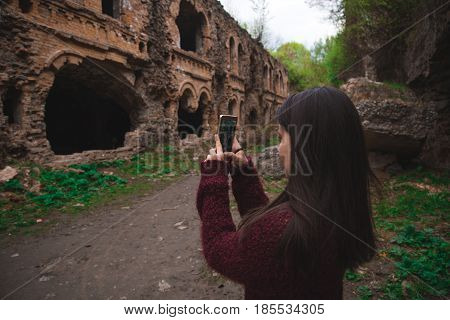 Young woman tourist photographing old ruins Tarakanovskiy fort Ukraine