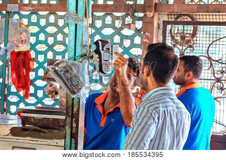 Bandar Abbas Hormozgan Province Iran - 16 april 2017: A Persian man pays a credit card for a purchase on the fish market using a mobile terminal.