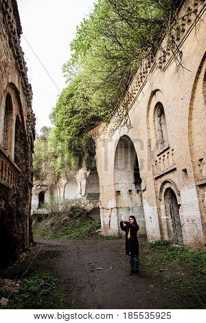 Young woman tourist photographing old ruins Tarakanovskiy fort Ukraine