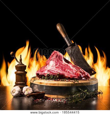Raw dry aged t-bone steaks for grill with fresh herbs and cleaver