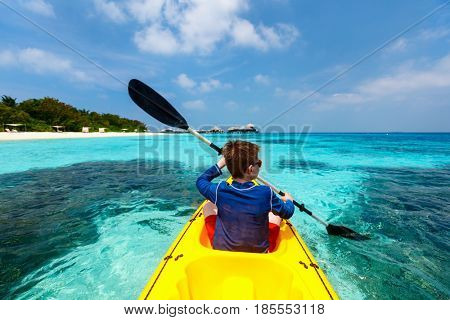 Back view of happy teenage boy on a kayak at tropical lagoon