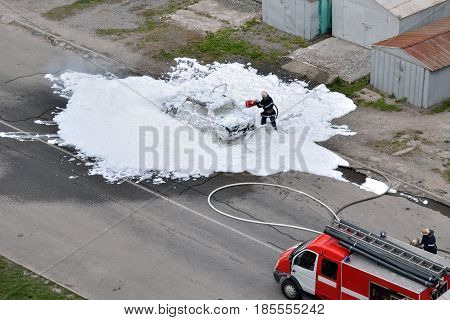 Firefighters are extinguished by a foam burning car. The work of special rescue services.