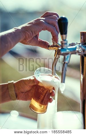 close-up of barman hand at beer tap pouring a draught lager beer