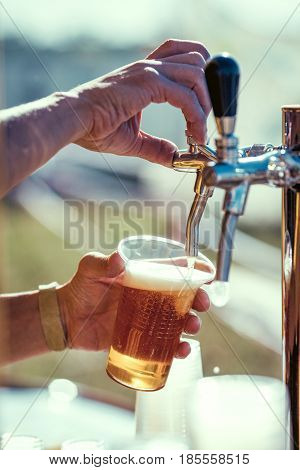 close-up of barman hand at beer tap pouring a draught lager beer