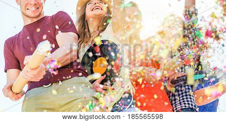Group of happy friends enjoying party and throwing confetti - Young people having fun outdoor dancing and listening music at sunset - Friendship and youth concept - Main focus on two right guys faces