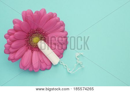 Menstruation tampon and pink gerbera daisy flower. Woman hygiene conception photo. Soft tender protection for woman critical days gynecological menstruation cycle