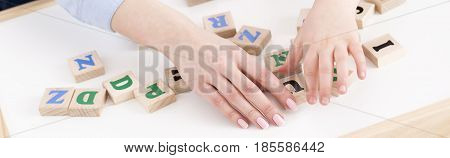 Close-up of teacher's and girl's hand placing the letters