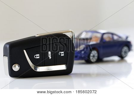 Car key with out of focus blue car in background. White background