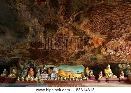 Beautiful panoramic view inside Kawgun Cave Hpa-An Myanmar (Burma). Lots of Buddha statues and ancient stucco on walls.
