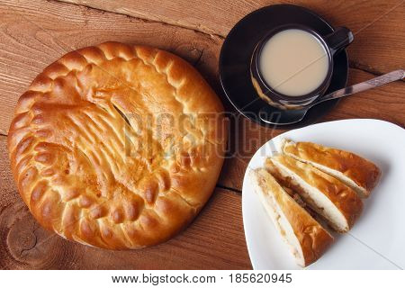 Fresh homemade apple pie and tea with milk on a wooden background