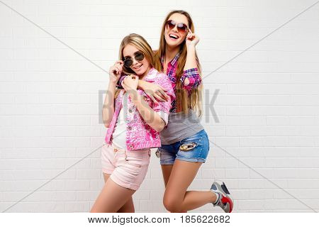 Fashion portrait of two friends posing. modern lifestyle.two stylish sexy hipster girls best friends ready for party.Two young girl friends standing together and having fun. Looking at camera.