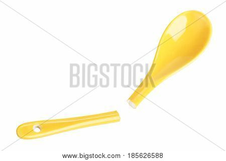 Broken yellow ceramic spoon on white background - fragility concept
