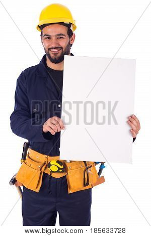 Handsome beard young worker smiling and holding a blankboard guy wearing workwear and yellow helmet with belt equipment isolated on white background