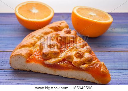 A piece of cake with orange confiture on a wooden table. Delicious dessert.