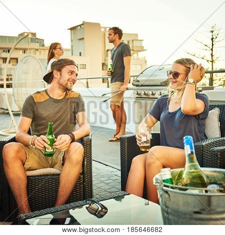 handsome young man flirting with a good looking young blonde woman in a social setting during a barbaque with friends and some alcohol to ease the tension.