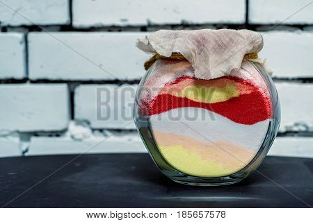 Souvenir glass jar filled with layers of sand of variuos colors