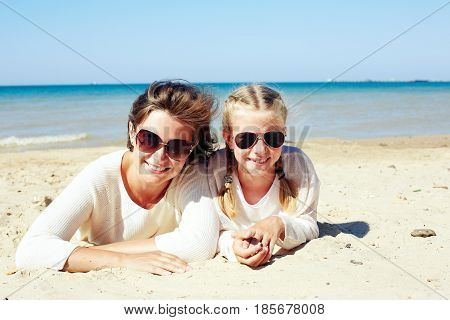 Daughter and her mom playing with sand on the beach