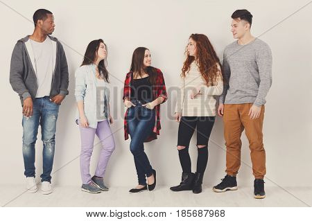 Education. Group of diverse students in casual outfits standing in line on white studio background