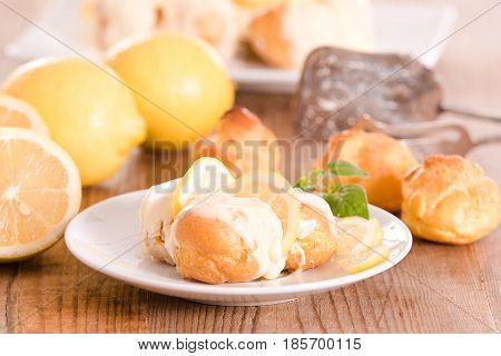 Lemon Profiteroles with custard cream on white dish.