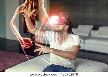 Young casual man playing on VR device with fiery sexy virtual woman silhouette indoors