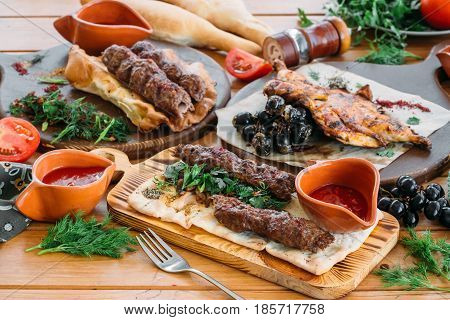 Minced meat Lyulya kebab with fresh vegetable and sauces on a serving table. Traditional Georgian dinner.