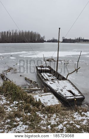 Two old wooden boat, one wrecked in a frozen river Tisa near Becej, Serbia. Winter time