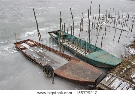 Two old wooden boat, one wrecked in a frozen river Tisa near Becej, Serbia. Winter time