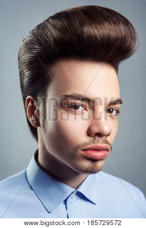 Portrait of young man with retro classic pompadour hairstyle. studio shot. looking at camera.